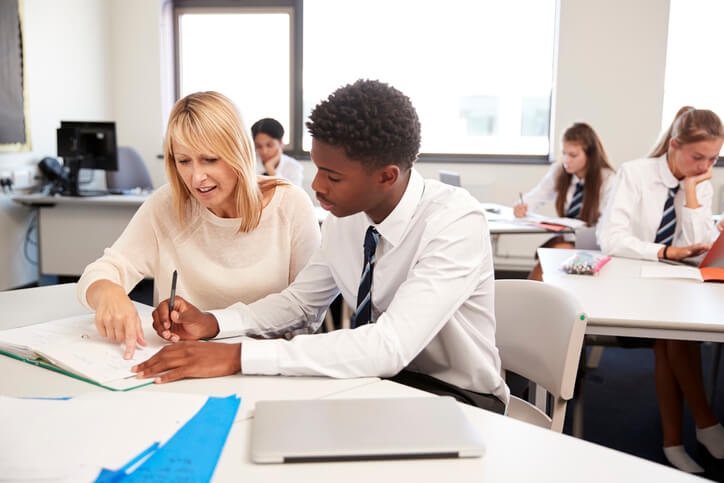 Dans notre école privée, un enseignant s'assoit à côté d'un élève pour l'aider dans son apprentissage.