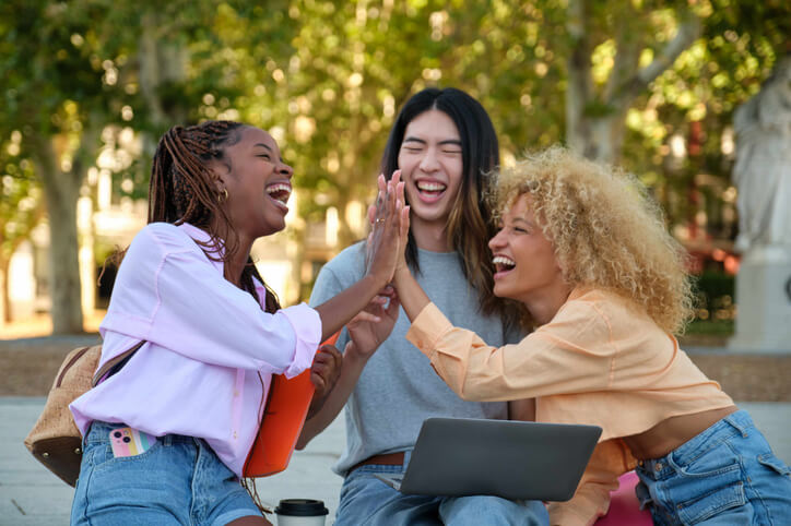 A trio of female students high-fiving at our private school